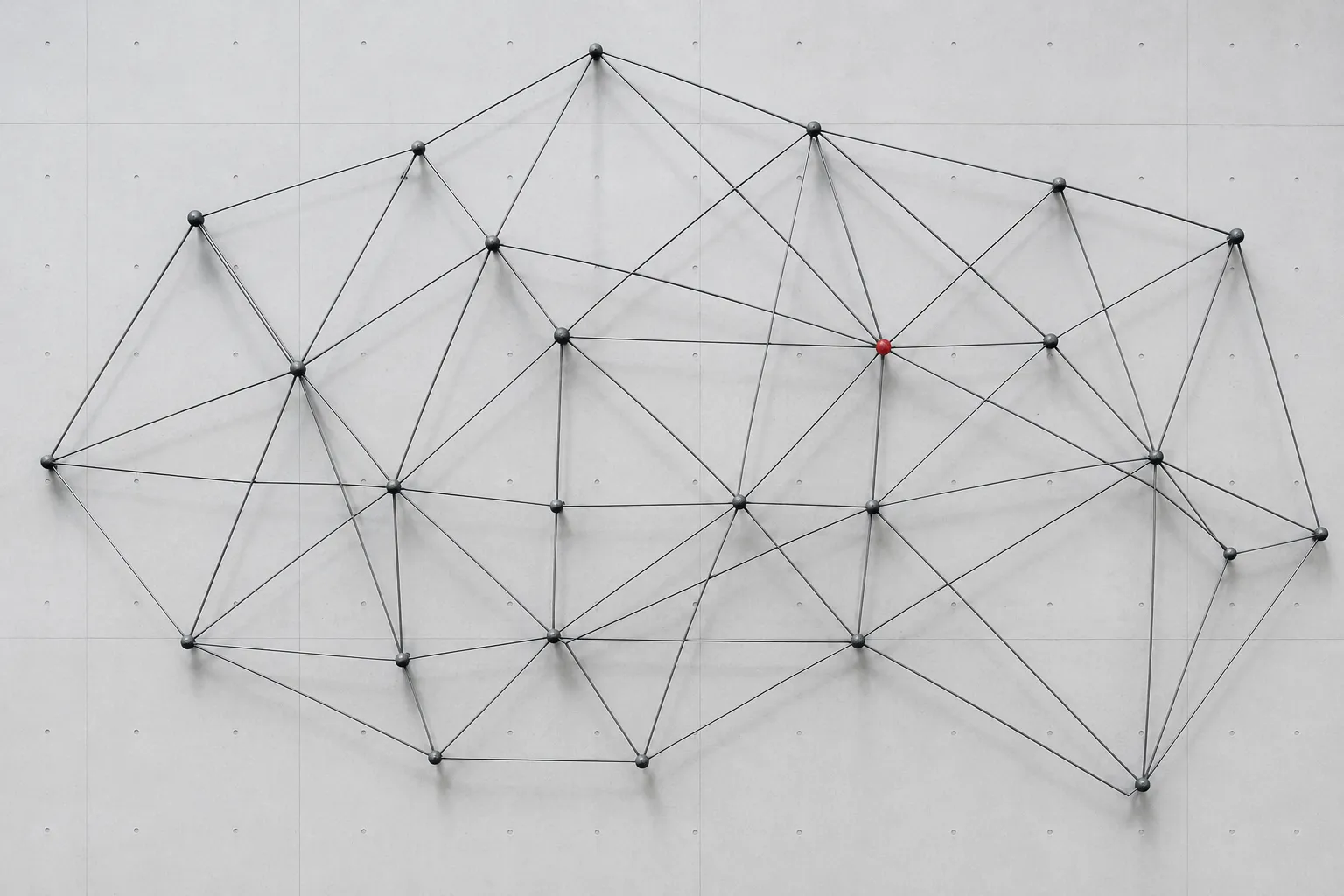 Abstrakte Wandinstallation aus dünnen Stahlstäben und Knoten.